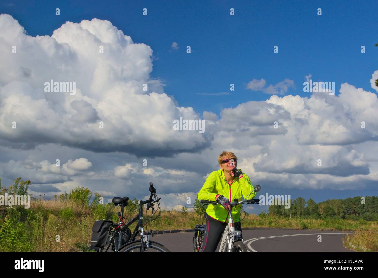 In bicicletta. Attraente donna di mezza età in abbigliamento sportivo in piedi accanto alla sua bicicletta con le mani sul volante. Foto Stock