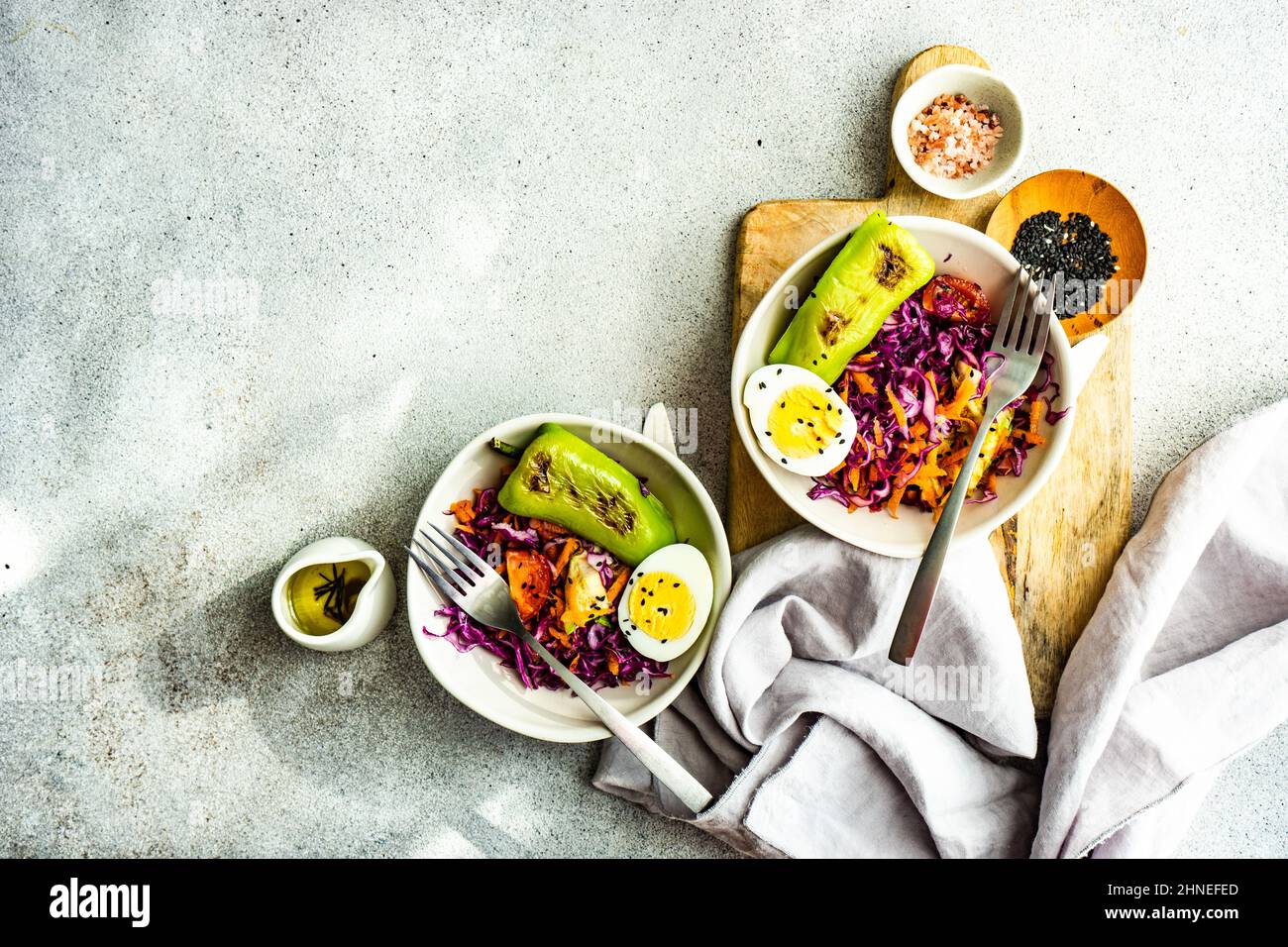 Due ciotole di cavolo rosso, carota, pepe verde e insalata di uova sode con olio d'oliva, semi di sesamo e sale rosa dell'Himalaya Foto Stock