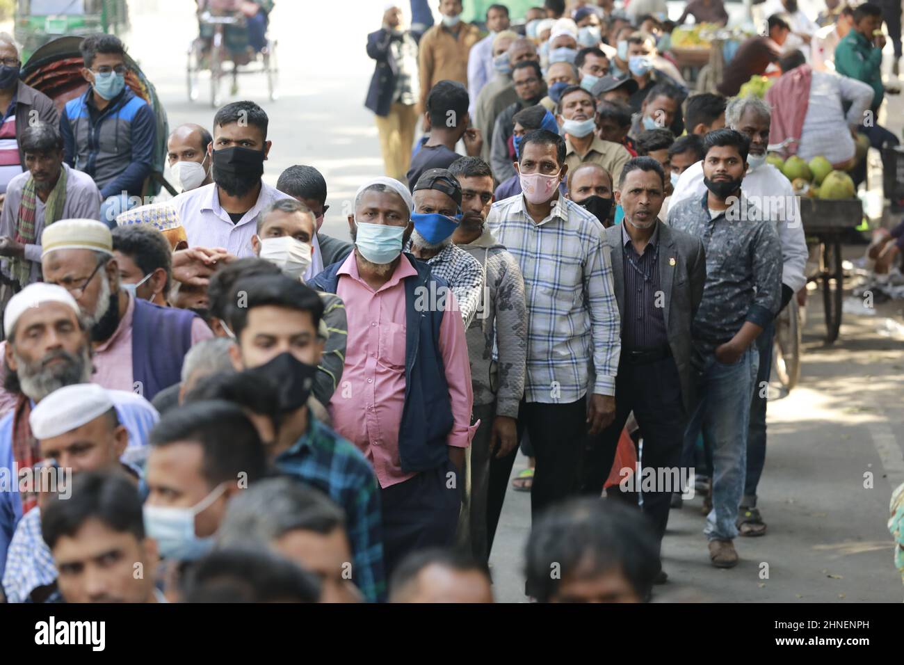 La gente del Bangladesh aspetta in coda per acquistare beni essenziali dalla Trading Corporation of Bangladesh Truck a un tasso agevolato, a Dhaka, Bangladesh, 16 febbraio 2022. La società di commercio statale del Bangladesh (TCB) vende tramite camion per fornire articoli essenziali tra le persone del gruppo a basso reddito a un prezzo agevolato. I prezzi di quasi tutti i beni di prima necessità sono saliti sul mercato della cucina, aggiungendo guai alle persone a reddito fisso che si stanno ribellando al rallentamento economico causato dalla pandemia. (Foto di Suvra Kanti Das/Sipa USA) Foto Stock