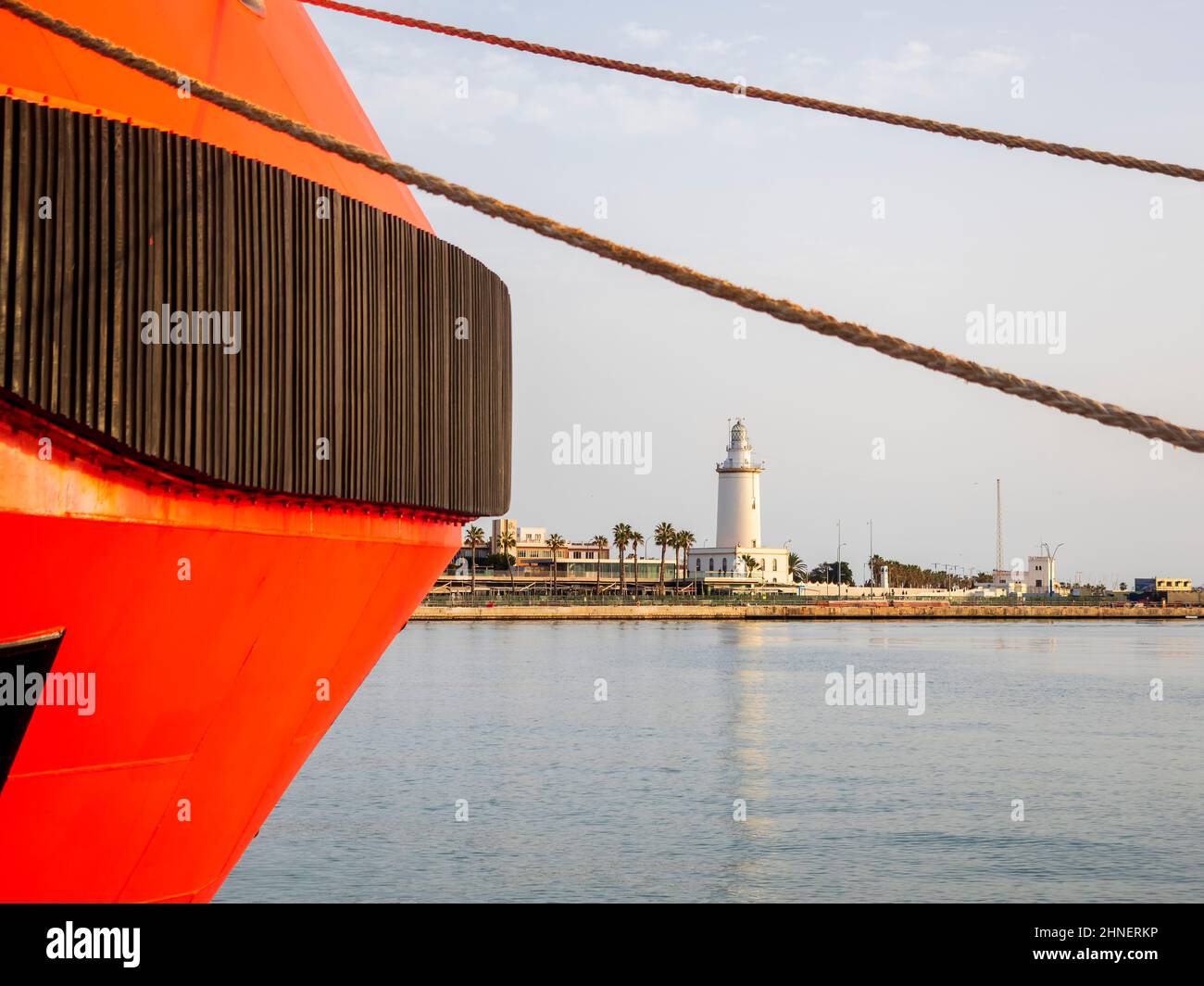 Primo piano di una barca da diporto con il faro del porto di Malaga sullo sfondo. Foto Stock