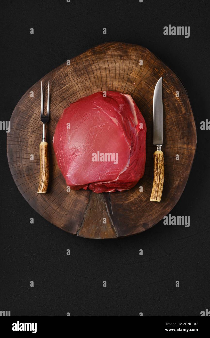 Carne rotonda di manzo crudo, intera sezione non tagliata su lastra di legno Foto Stock