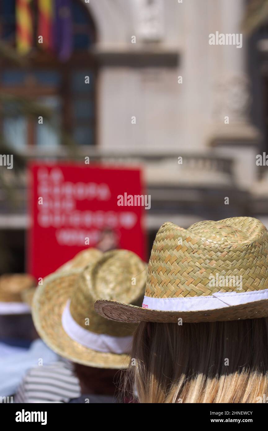 Primo piano di una donna irriconoscibile al pubblico in un evento all'aperto in cui tutti indossano un cappello di paglia per proteggersi dal sole Foto Stock