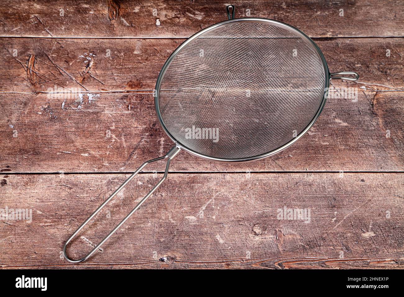 Tavolo da cucina in legno con setaccio in acciaio inox, concetto di cottura Foto Stock