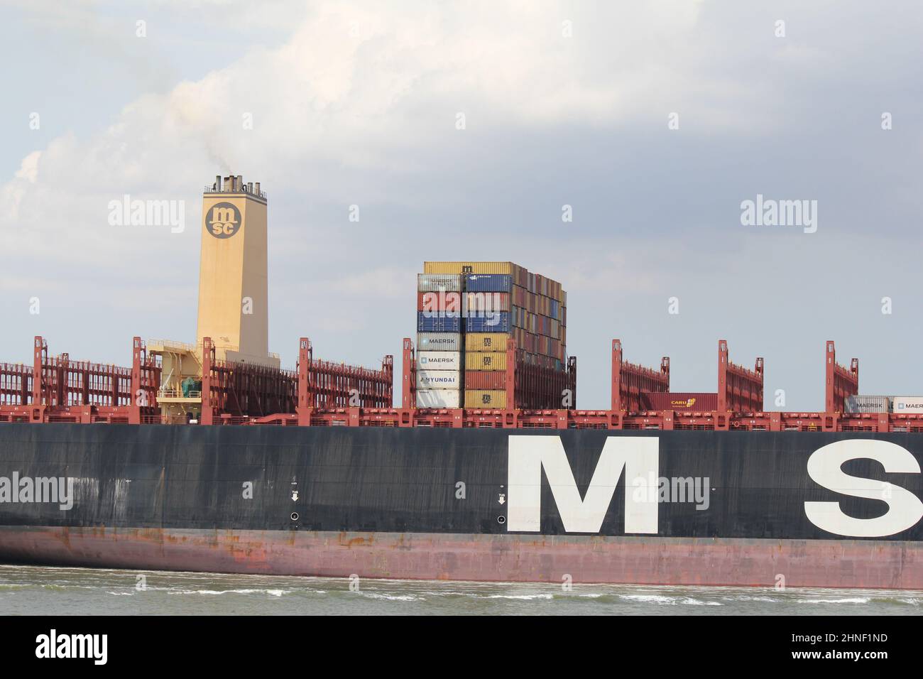 il centro di una grande nave da carico con alcuni fiocchi di container marini in primo piano nel mare westerschelde nei paesi bassi in estate Foto Stock