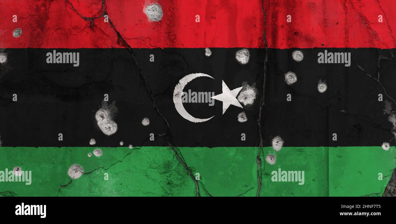 Foto full frame di una bandiera della Libia intemperie dipinta su una parete incrinata con fori proiettili. Concetto di crisi libica, conflitto e guerra civile. Foto Stock