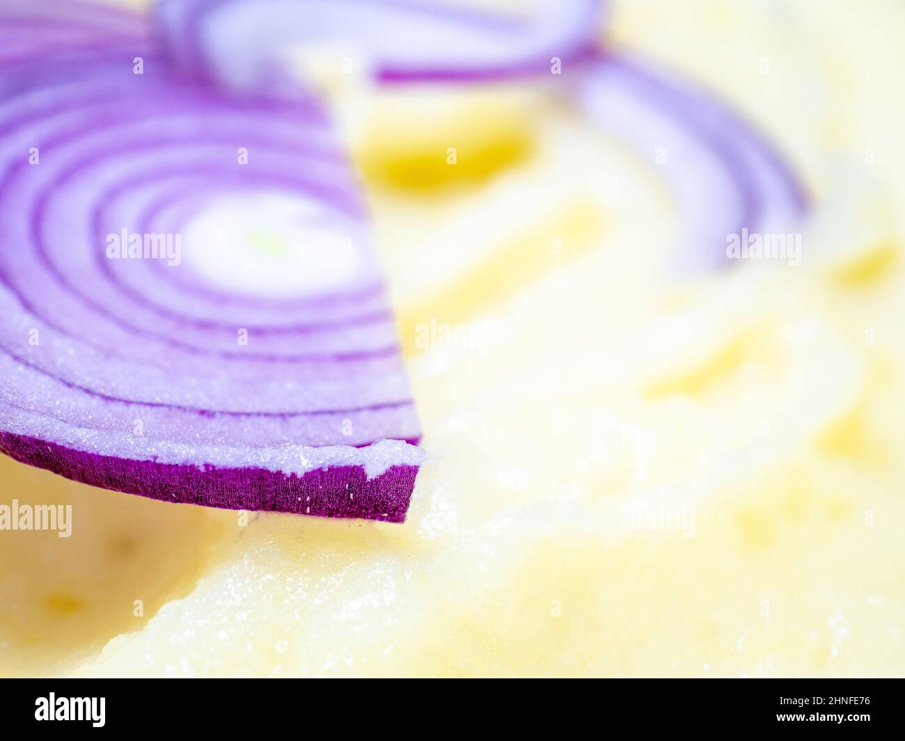 Fuoco selettivo sugli anelli rossi della cipolla nelle patate schiacciate. Foto Stock