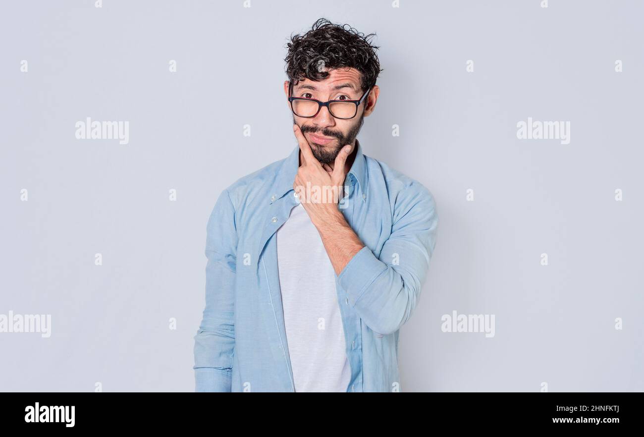 Uomo che strofina la barba con un'espressione di dubbio, immagine di un bell'uomo barbuto con un'espressione di dubbio Foto Stock