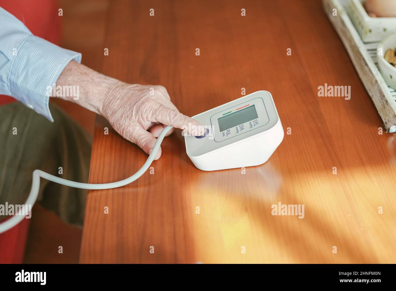 il vecchio uomo preme il pulsante di avvio per prendere la pressione sanguigna Foto Stock