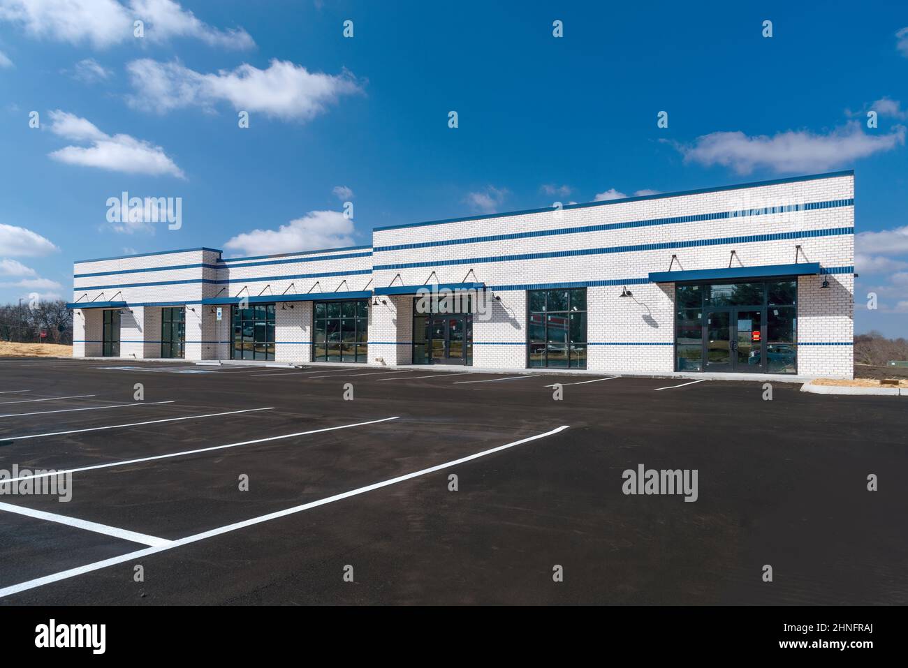 Foto orizzontale di un nuovo centro commerciale business strip costruito con un parcheggio nuovo di zecca con strisce dipinte di fresco. Foto Stock