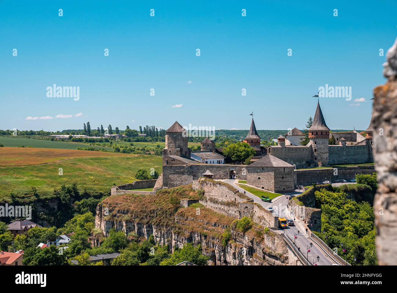 Kamianets Podilskyi Castello contro il cielo con traffico auto su strada.. Foto Stock