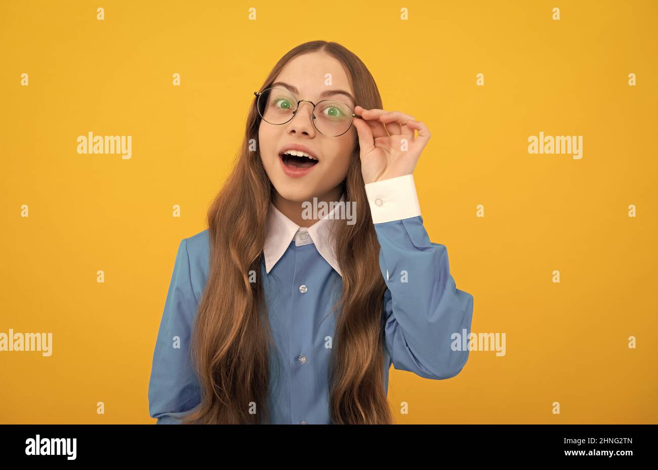 Curioso scuola età ragazza bambino sguardo attraverso occhiali sfondo giallo, curiosità Foto Stock