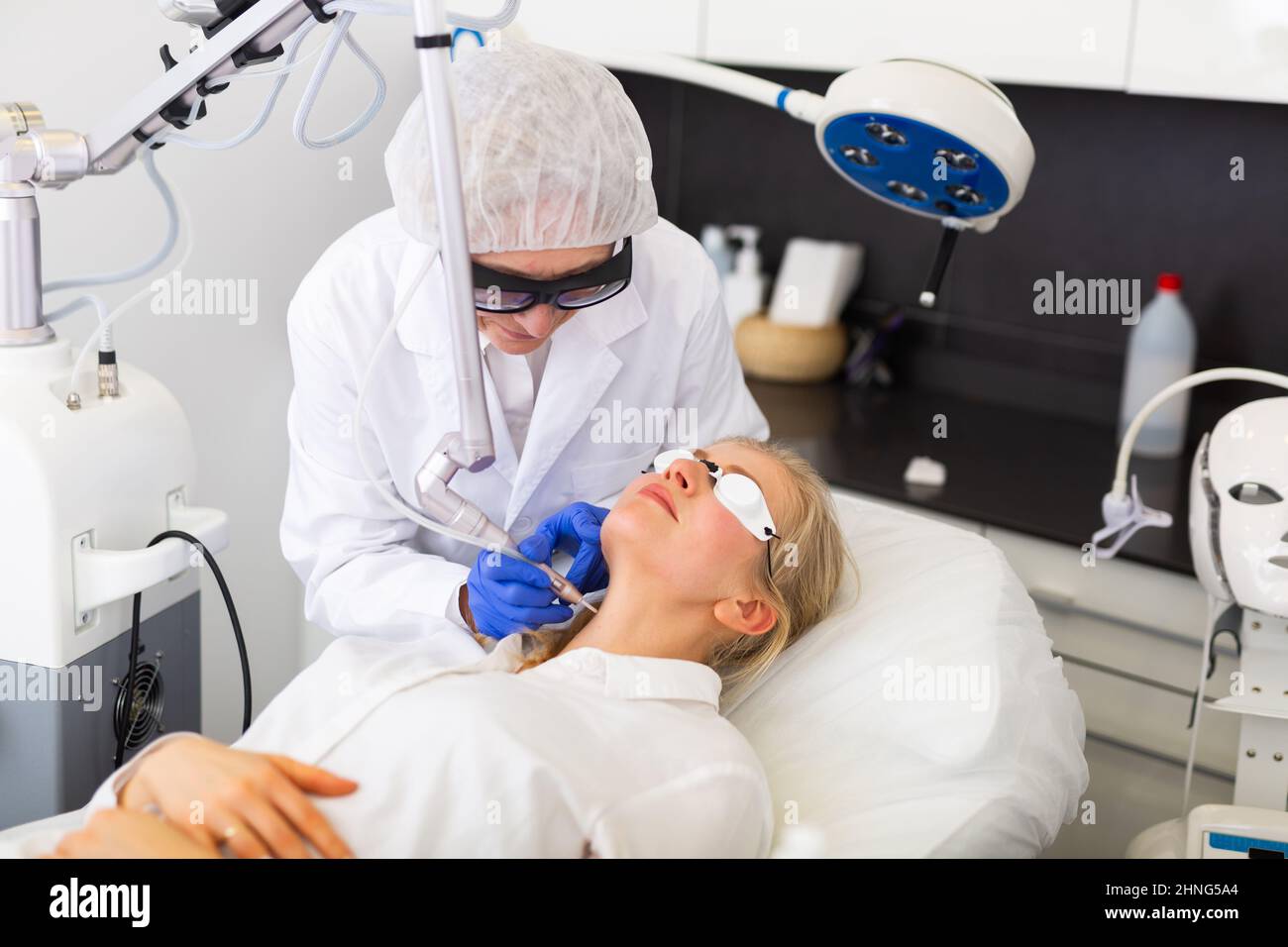 Cosmetologo esperto che esegue il trattamento laser facciale alla giovane donna Foto Stock