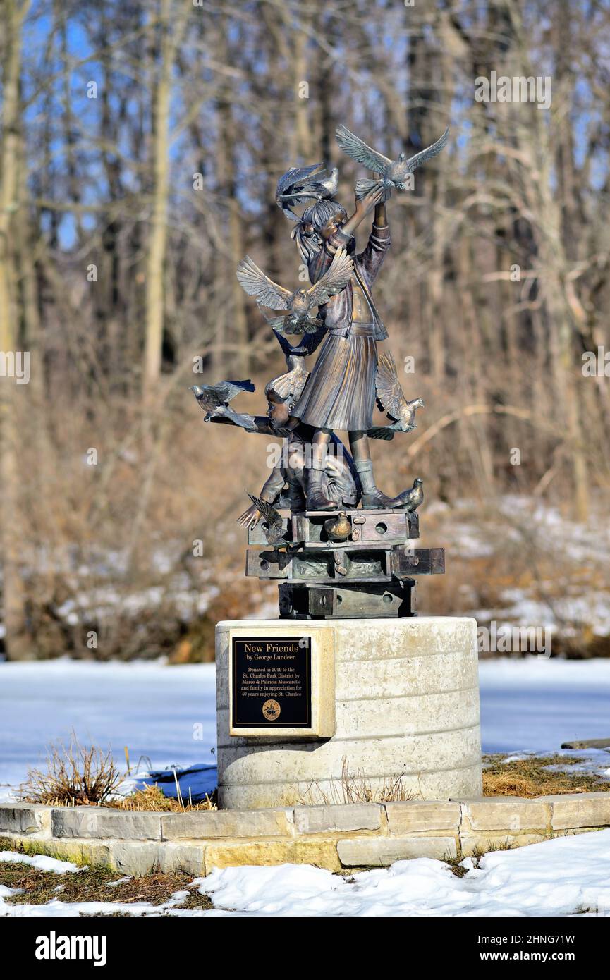 St. Charles, Illinois, Stati Uniti. Una statua, "New Freinds" di George Lundeen graces una riva del torrente in un parco, congelato nel tempo, come il suo inverno circostante. Foto Stock