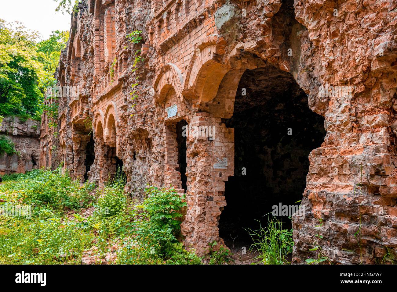 Mattoncini vecchi crumbling di vecchio forte abbandonato circondato da piante verdi Foto Stock