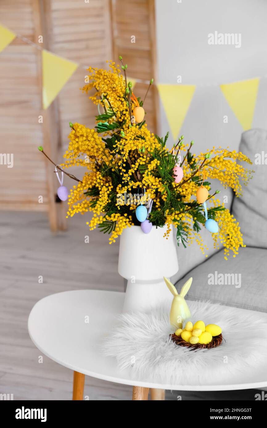 Vaso con fiori di mimosa, uova di Pasqua e decorazioni sul tavolo in  soggiorno Foto stock - Alamy
