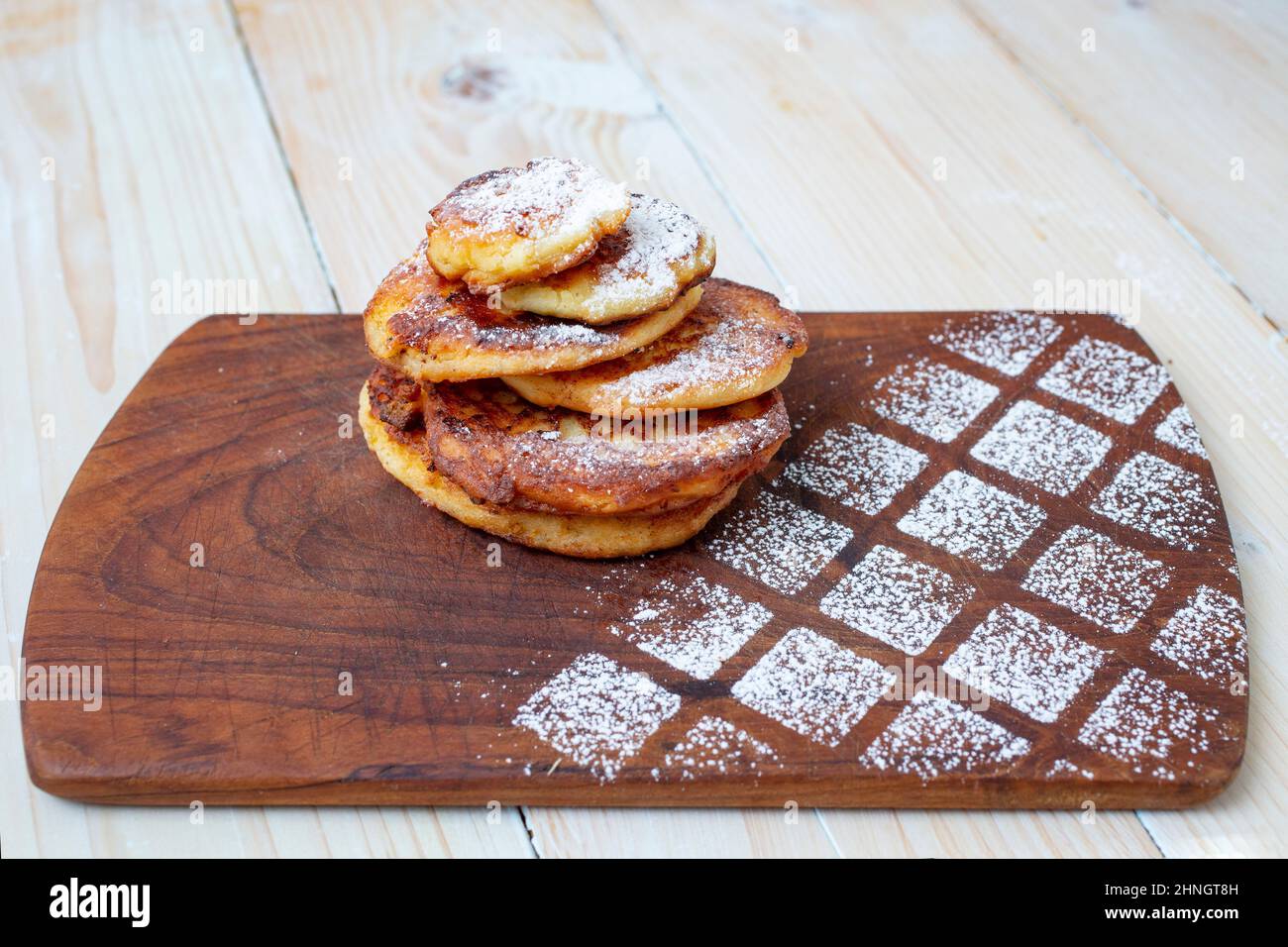 Papanasi rumena o pancake al formaggio casolare su un tritatutto in legno rustico Foto Stock
