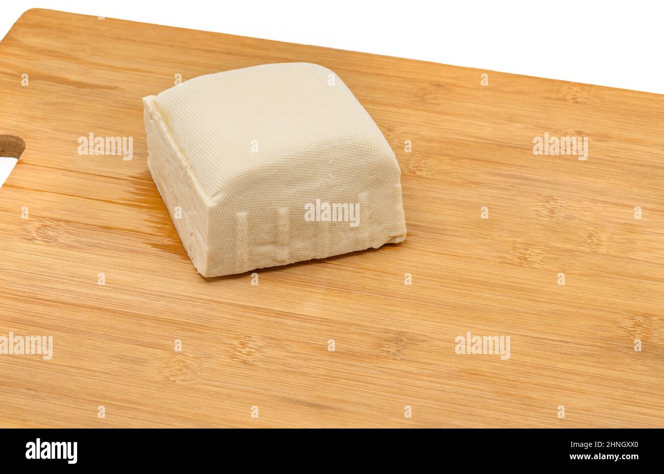 Primo piano un tofu solido su un tagliere di legno, tofu bianco o tofu medio duro con forma di chubby, spazio vuoto per il testo. Dettagli sul tofu fresco Foto Stock