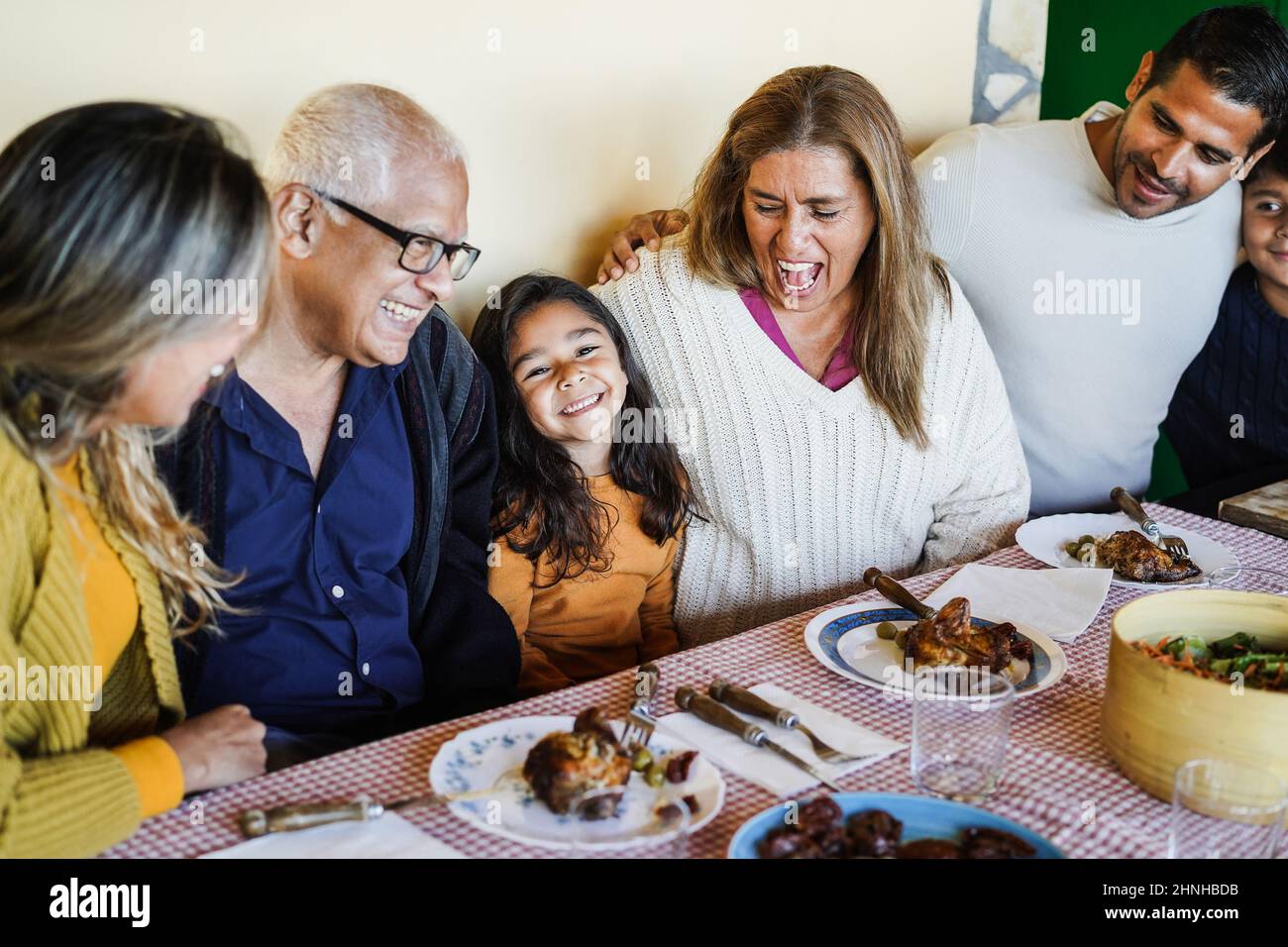 Felice famiglia latina divertirsi mangiando insieme a casa - Focus sulla faccia della nonna Foto Stock