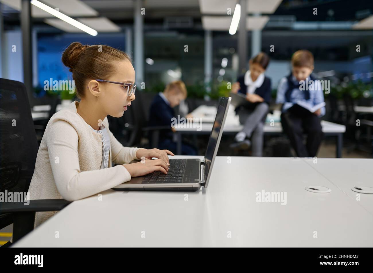 Bambina che lavora sul laptop in ufficio Foto Stock