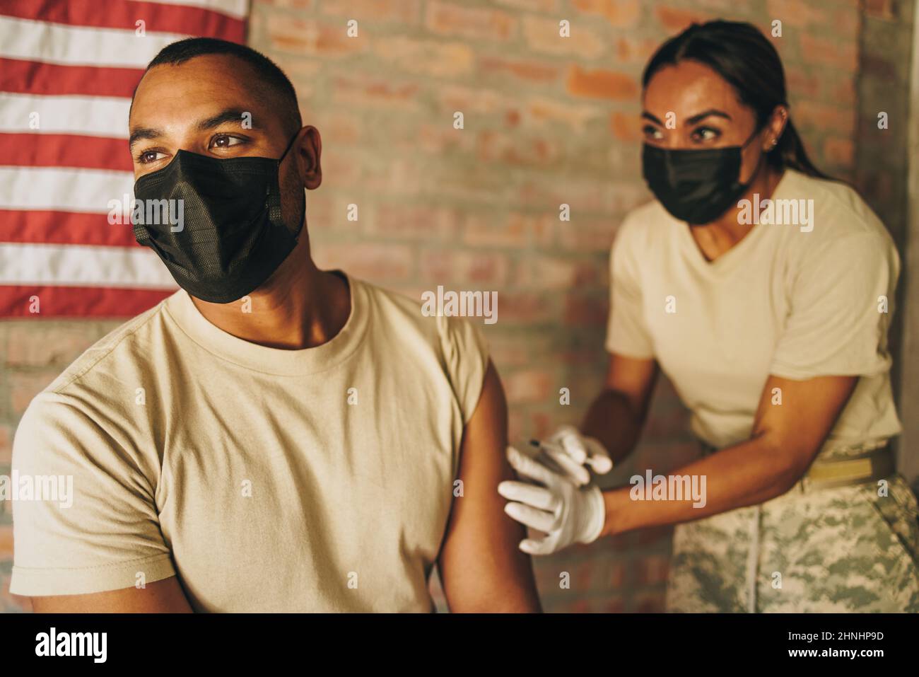 Soldato che riceve un richiamo del vaccino covid-19 da un medico dell'esercito. Il serviceman degli Stati Uniti ottiene inoculato contro la malattia di coronavirus in Foto Stock