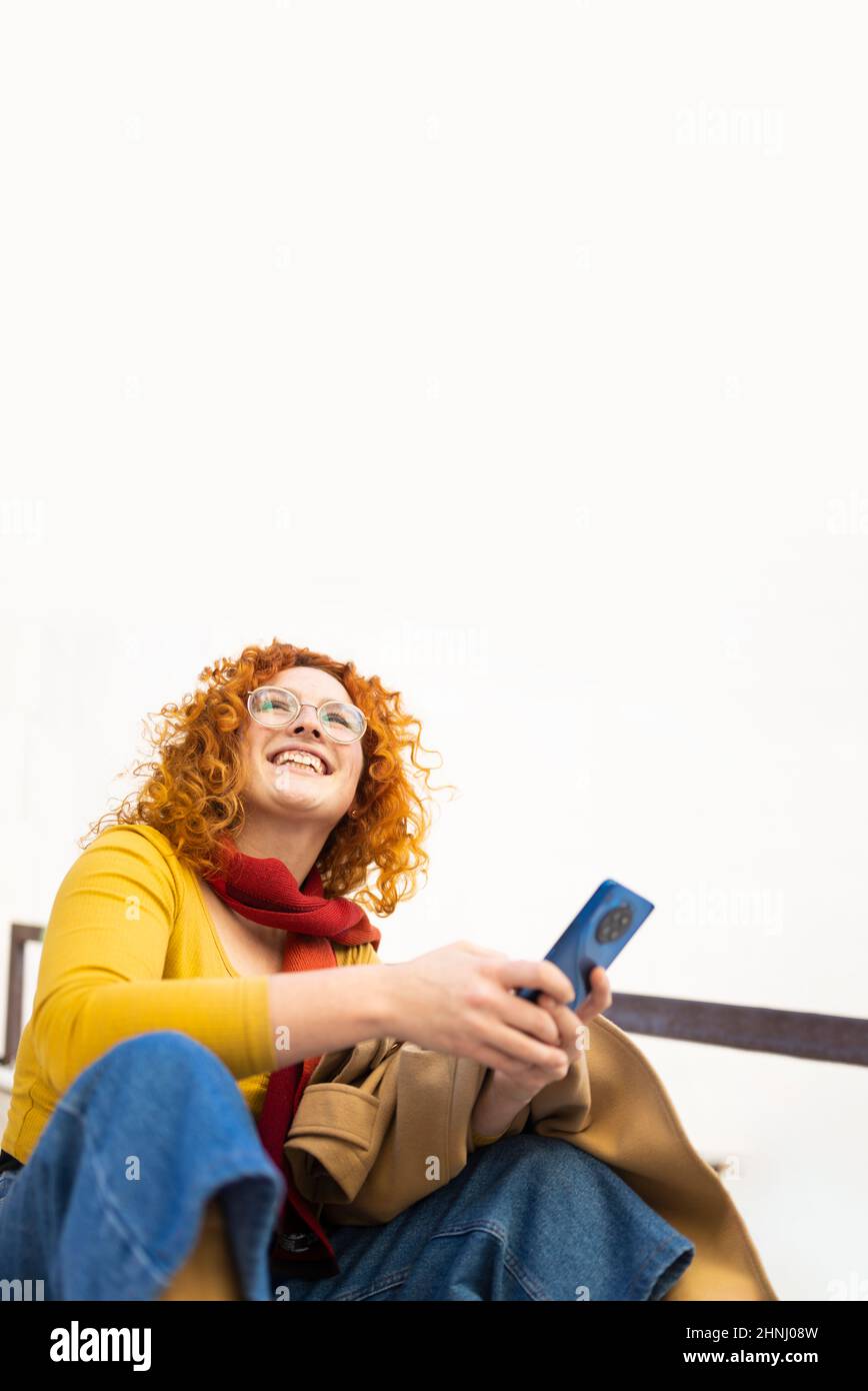 Giovane donna ricciola che usa il suo smartphone in una bella giornata Foto Stock