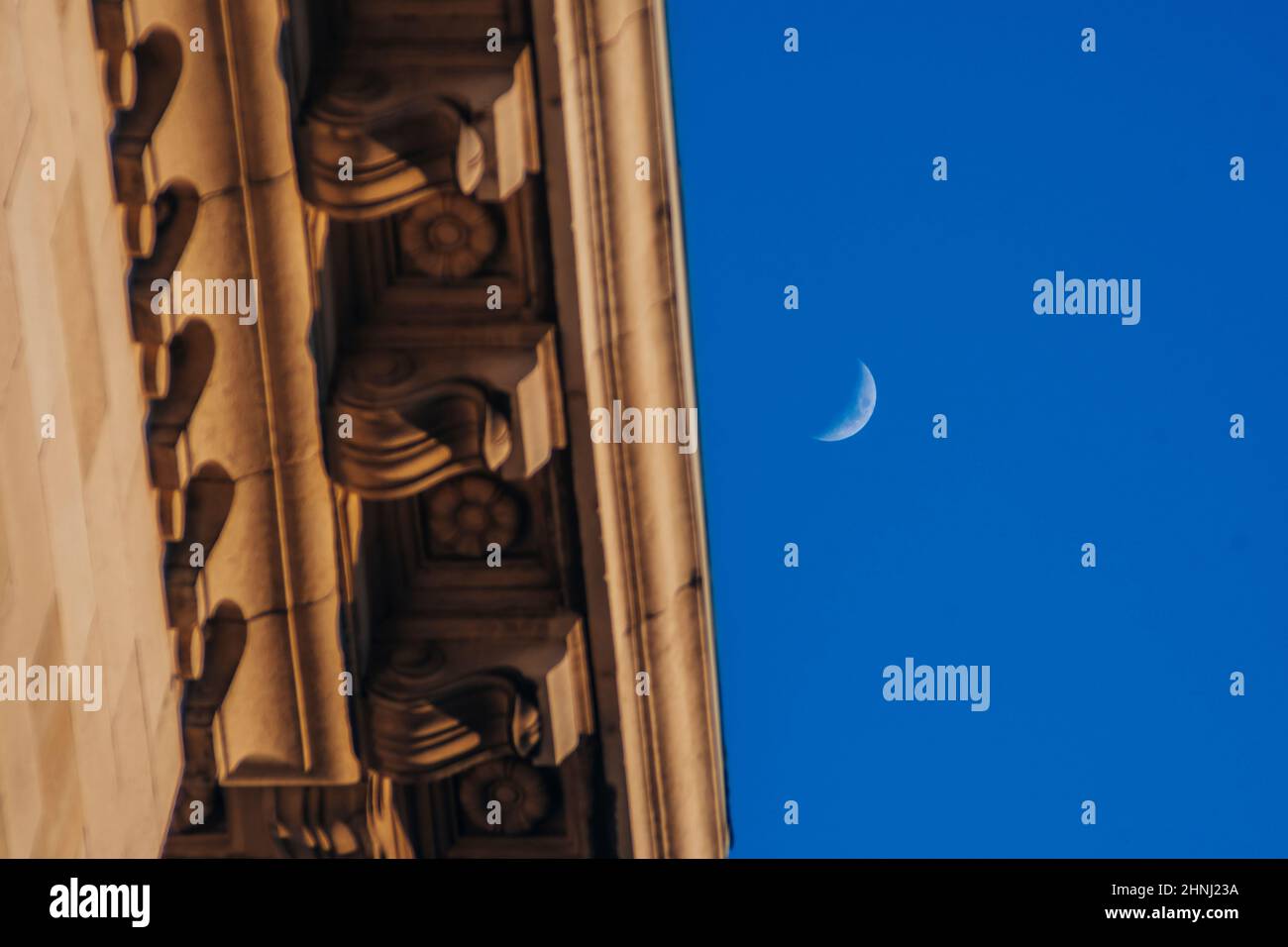 Luna Crescent durante il giorno al tramonto accanto ad un tetto in arancione giallo chiaro. Bellissimo paesaggio carta da parati. Foto di alta qualità Foto Stock