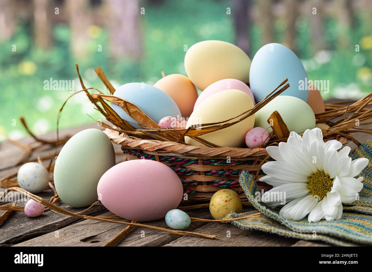 Colorate uova di pasqua in un cestino e su un rustico tavolo in legno con sfondo rurale Foto Stock