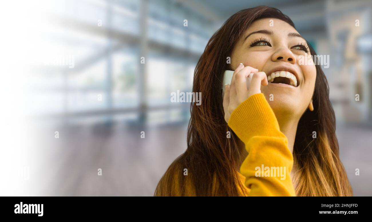 Giovane donna asiatica che ride mentre parla con lo smartphone Foto Stock