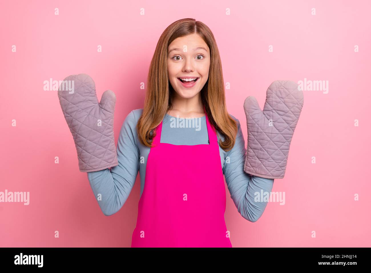 Ritratto di attraente divertente ragazza allegro indossare grembiule guanti cucina domestica isolato su sfondo rosa pastello colore Foto Stock