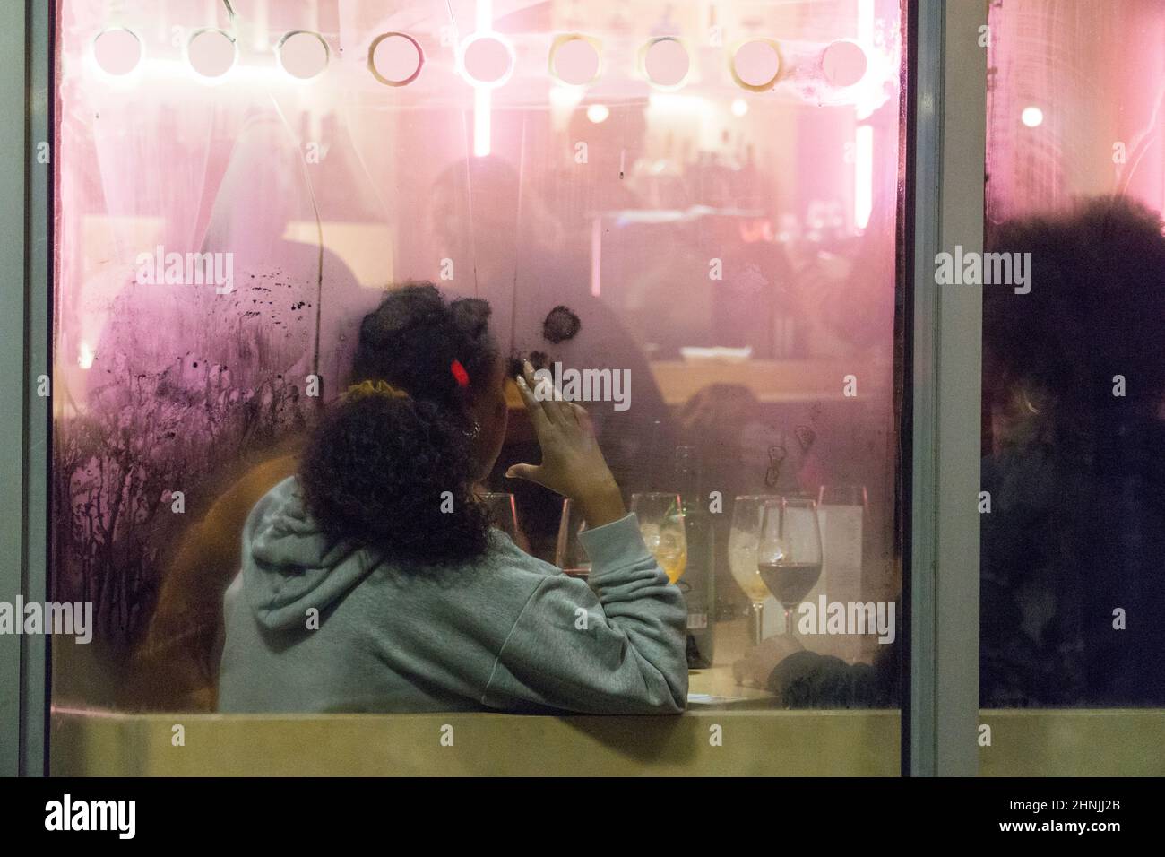 Londra, UK, 16 febbraio 2022: Al bar del cinema Curzon Soho un gruppo di persone si siedono a un tavolo con bevande in bicchieri da vino, bagnata dalla luce rosa delle luci al neon. Poiché l'Inghilterra ha ridotto le restrizioni covidi ai livelli del piano A, e le rimuoverà interamente all'inizio della prossima settimana, i settori dell'ospitalità e dell'intrattenimento sperano in un rimbalzo finanziario dopo le perdite della pandemia. Anna Watson/Alamy Live News Foto Stock