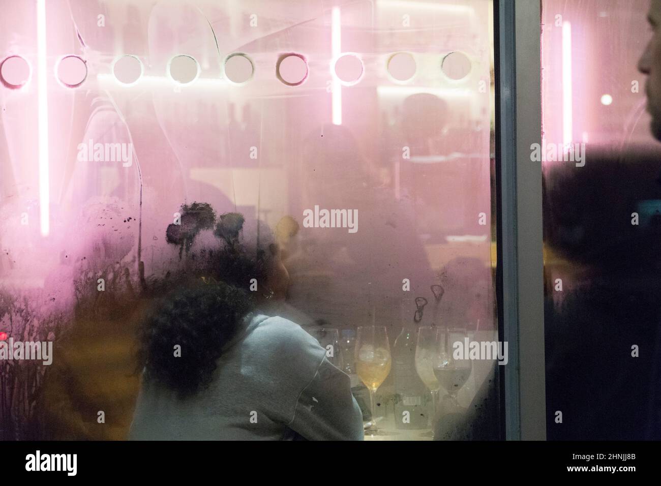 Londra, UK, 16 febbraio 2022: Al bar del cinema Curzon Soho un gruppo di persone si siedono a un tavolo con bevande in bicchieri da vino, bagnata dalla luce rosa delle luci al neon. Poiché l'Inghilterra ha ridotto le restrizioni covidi ai livelli del piano A, e le rimuoverà interamente all'inizio della prossima settimana, i settori dell'ospitalità e dell'intrattenimento sperano in un rimbalzo finanziario dopo le perdite della pandemia. Anna Watson/Alamy Live News Foto Stock