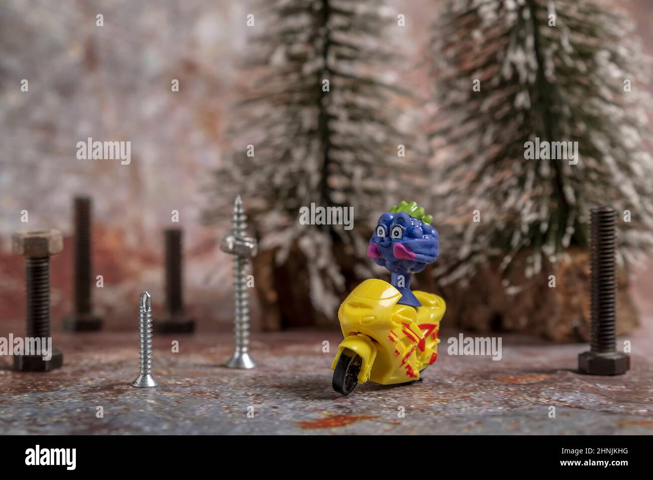 Un pupazzo di gomma di vari colori su un modello di moto giallo in un ambiente urbano realizzato con viti e bulloni Foto Stock