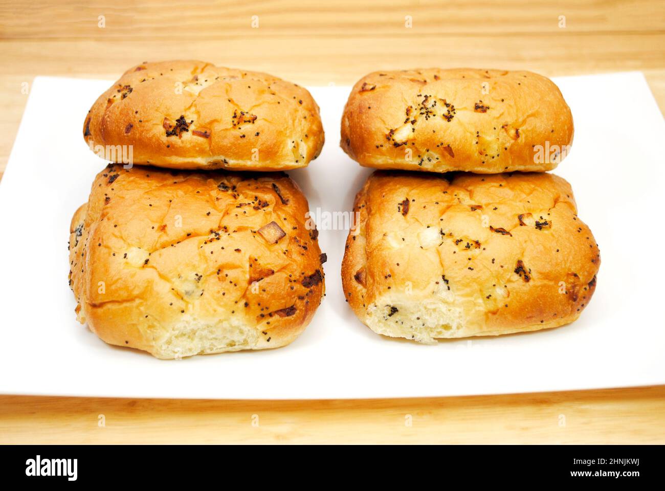 Quattro rotoli di cipolla su un piatto bianco Foto Stock