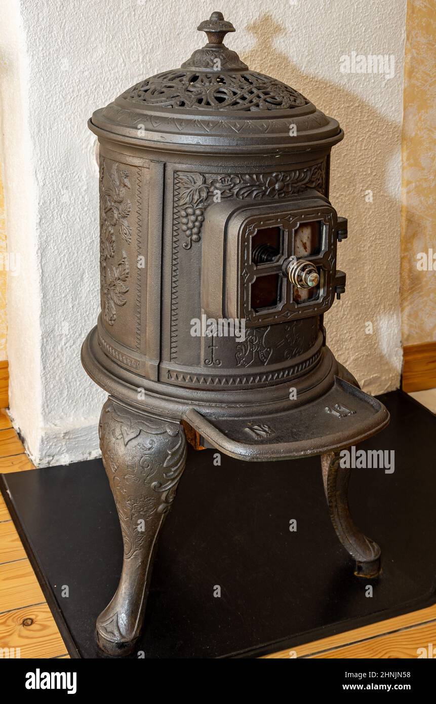 Tradizionale stufa rustica classica in ghisa davanti a una parete bianca. Foto Stock