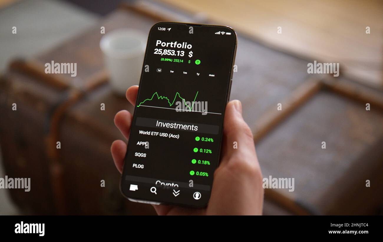 Telefono di tenuta della mano con l'app di commercio Mockup che osserva il mercato azionario e gli investimenti che aumentano in dollaro Foto Stock