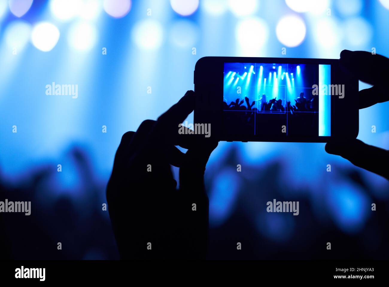 Scatto ritagliato di una persona che filma la loro band preferita con un telefono con fotocamera. Questo concerto è stato creato per il solo scopo di questo scatto fotografico, in scena Foto Stock