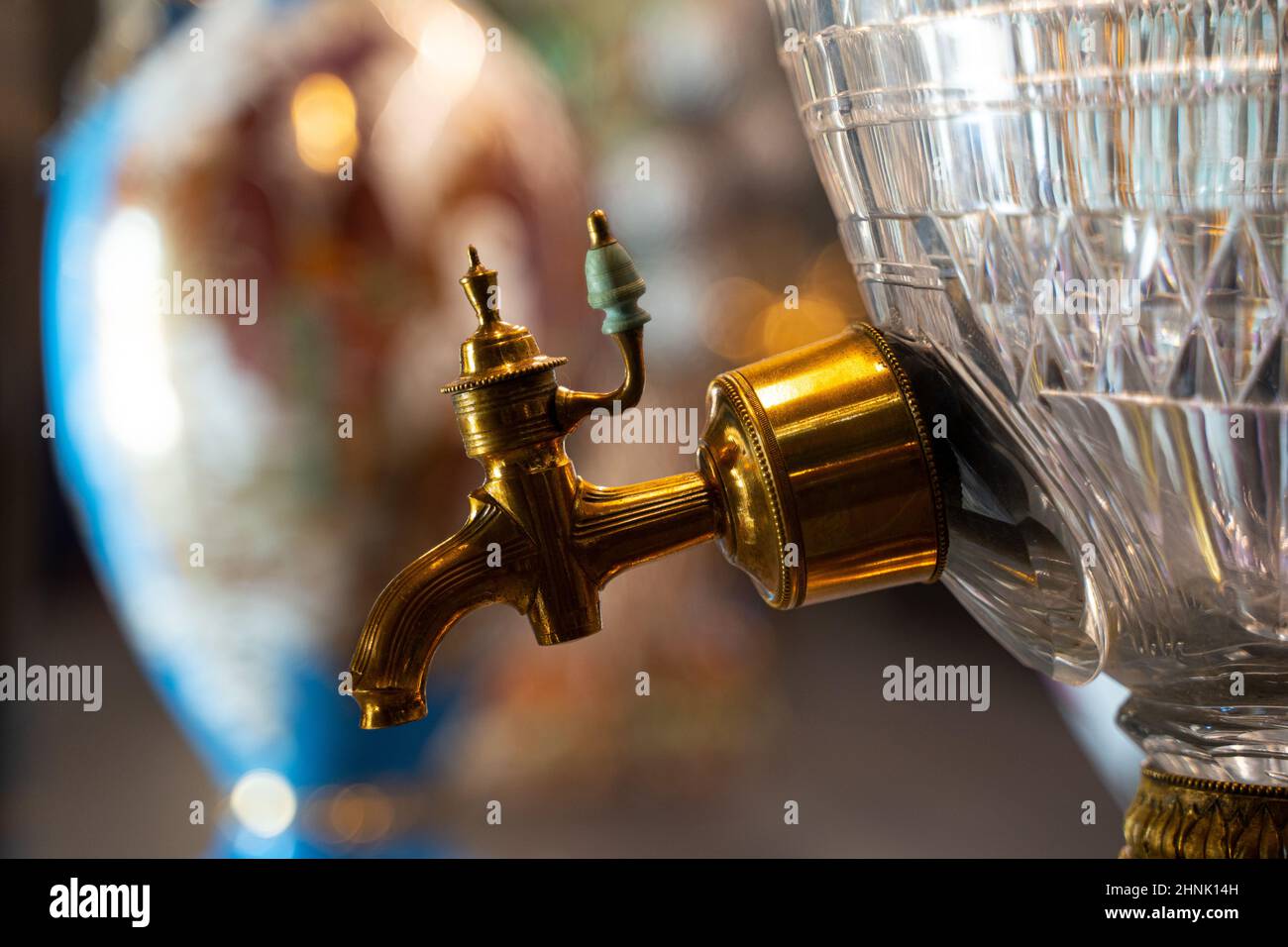 vista laterale primo piano di un bellissimo rubinetto dorato con manico in ceramica di lussuoso samovar in vetro Foto Stock