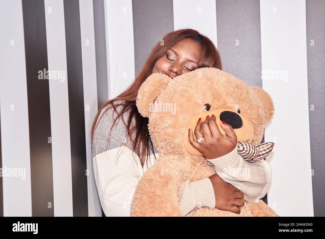 Donna felice che riceve orsacchiotto. Sfondo bianco e nero. I suoi occhi sono chiusi. Concetto di vacanza, compleanno, Giornata Mondiale della Donna o San Valentino, Foto Stock