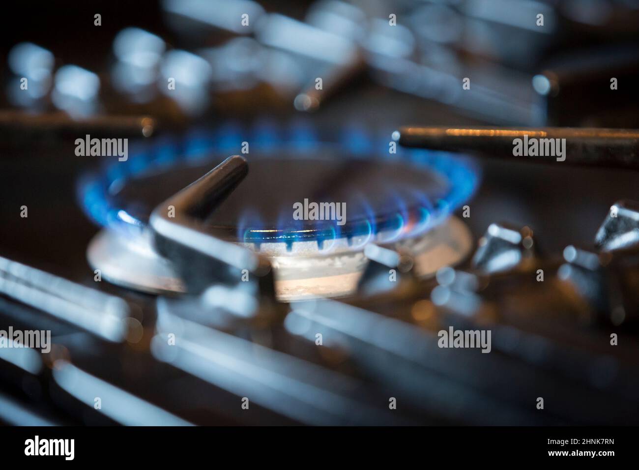 Primo piano di gas fiammeggiante anello illuminato sul piano di cottura di una cucina a gas domestico in un ambiente di cucina britannico. Foto Stock