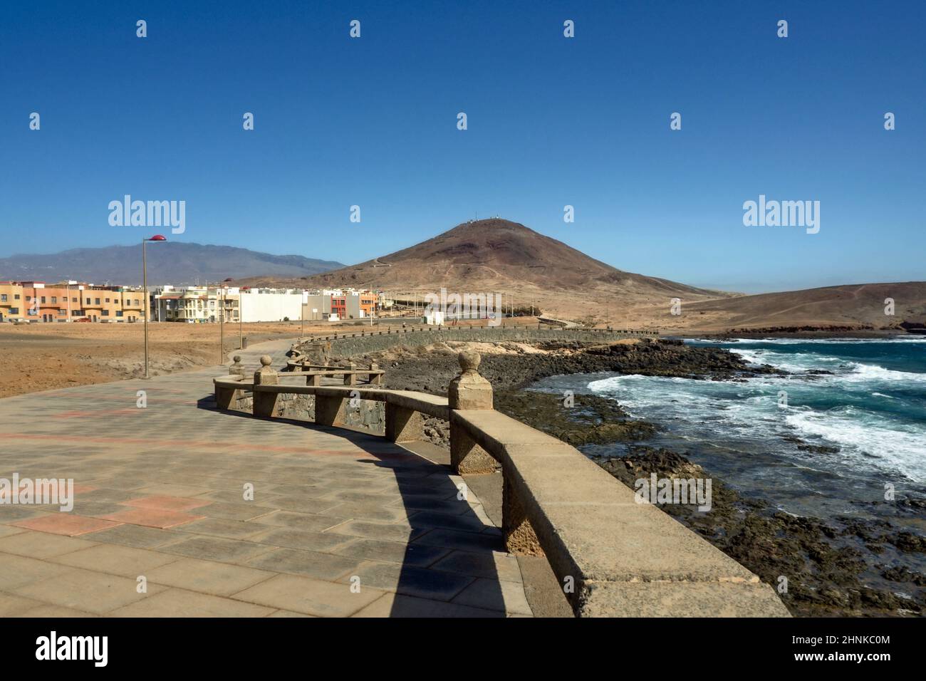 La fine del lungomare di Arinaga sulla costa meridionale dell'isola delle Canarie di Gran Canaria. A destra l'Atlantico, a sinistra il marciapiede lastricato, b scuro Foto Stock