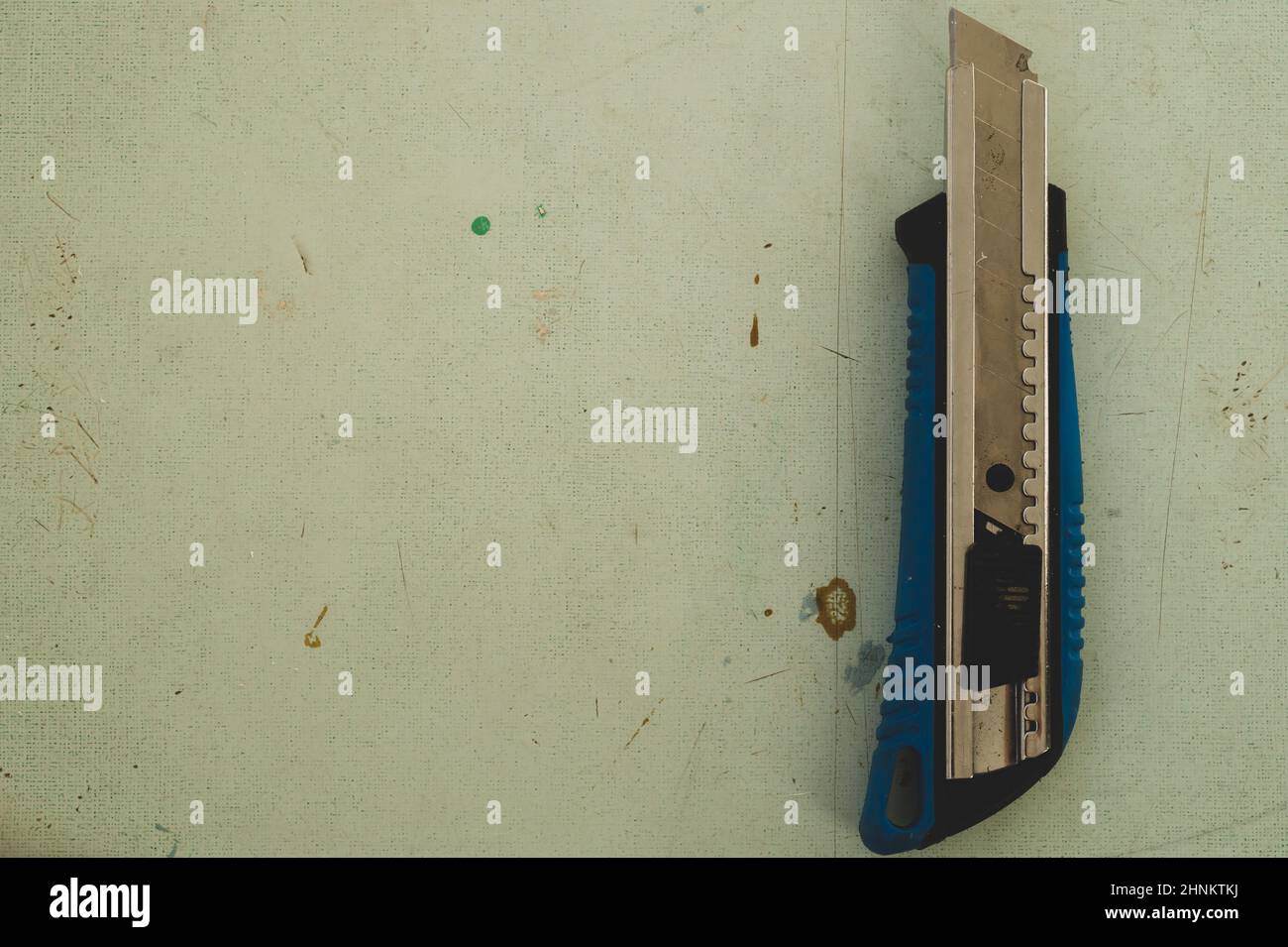 Coltello per cancelleria sul pavimento in legno. Coltello per taglierina sul piano di lavoro Foto Stock