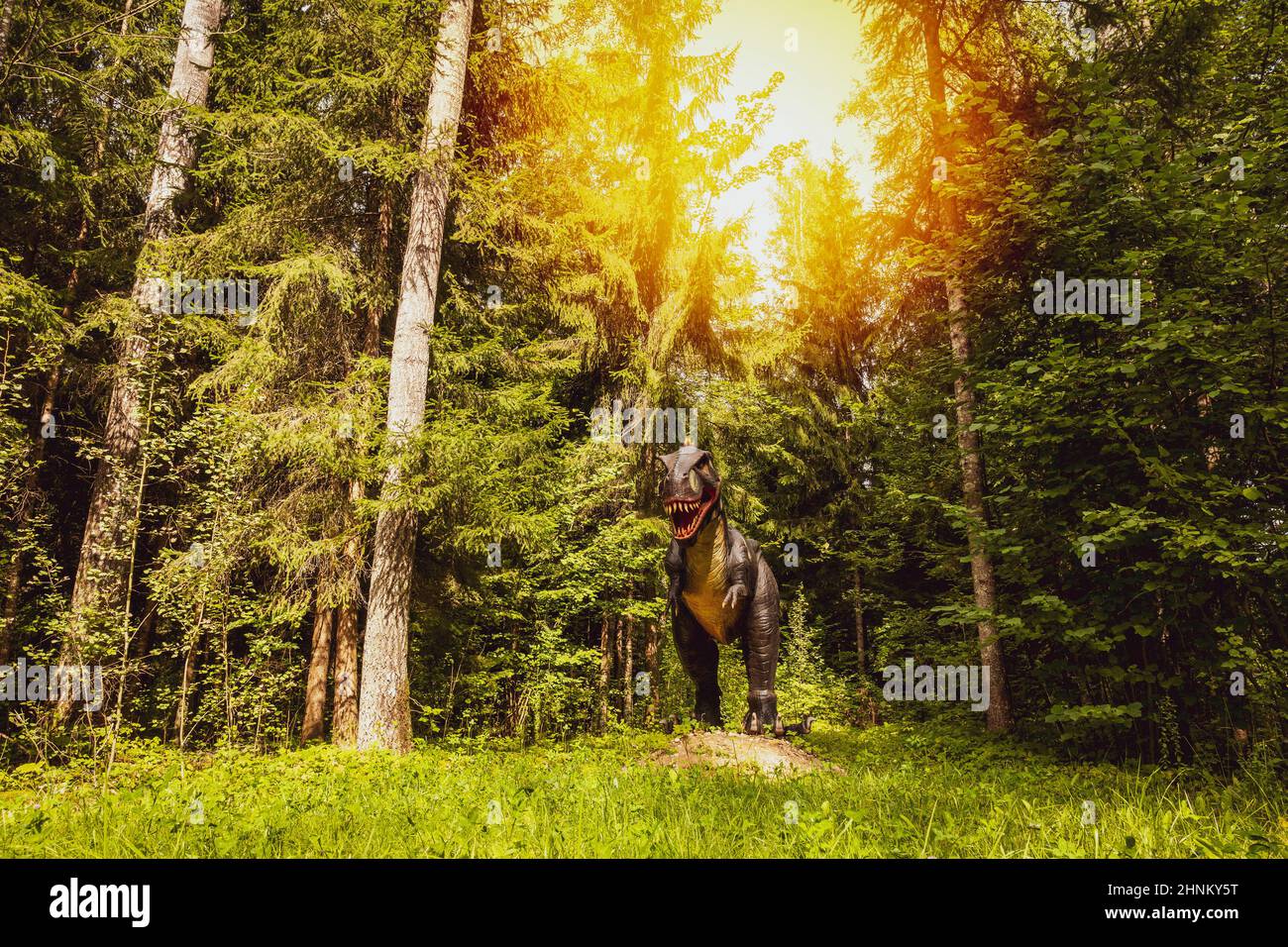 Statua di dinosauro in una foresta con alberi alti Foto Stock