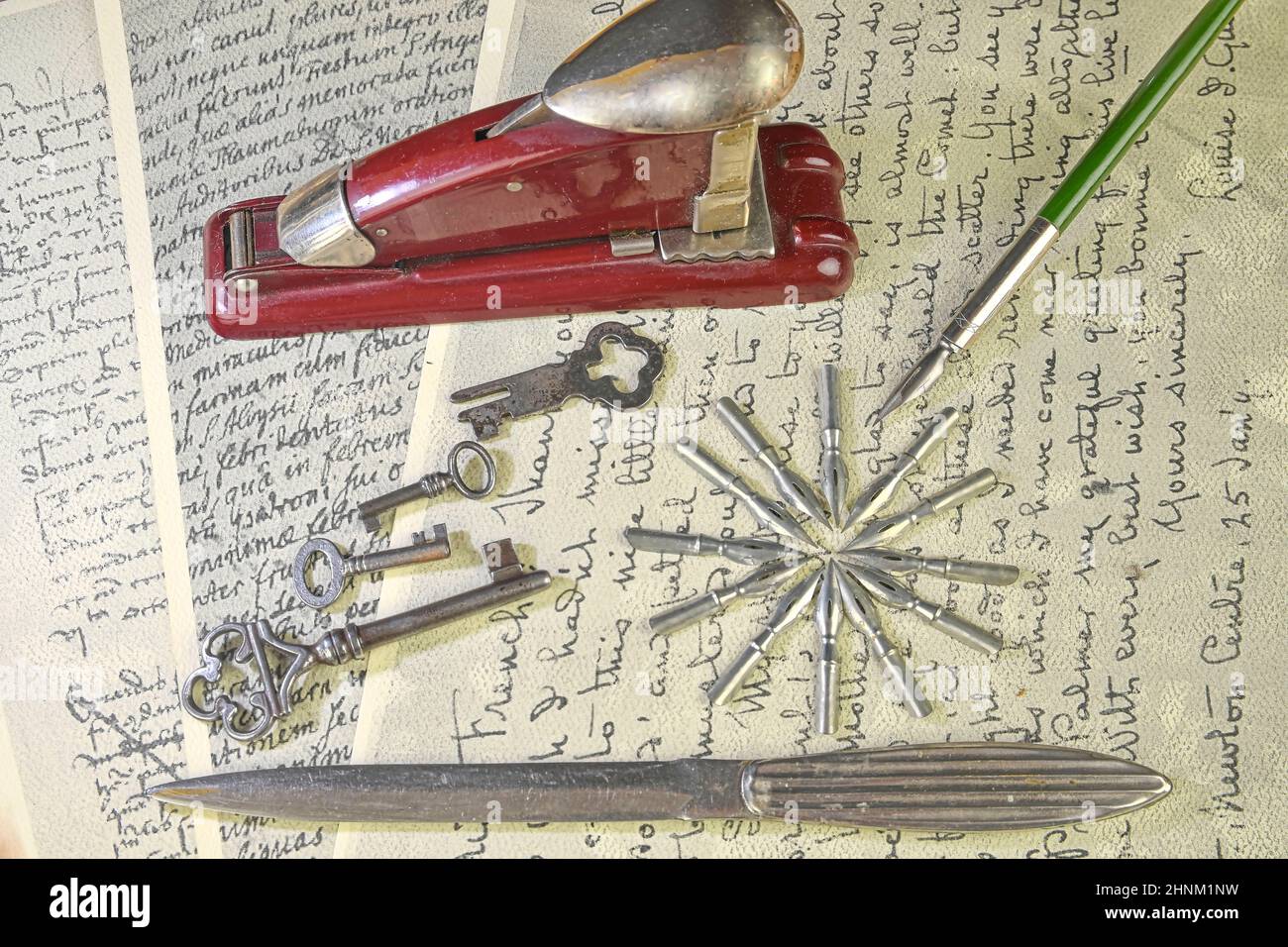 Primo piano degli accessori sulla scrittura vintage. Tasti vintage, pinzatrice, coltello per carta, pennini metallici e penna vecchia. Cancelleria d'epoca. Disposizione piatta Foto Stock