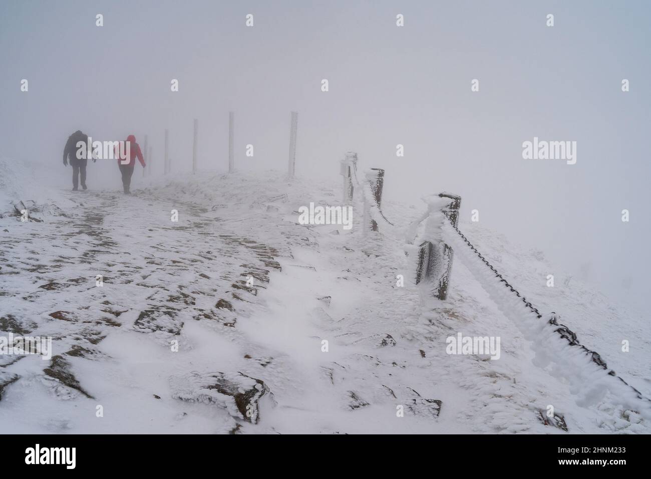 Strada invernale in salita in cattive condizioni meteorologiche. I viaggiatori salgono la strada in salita. Foto Stock