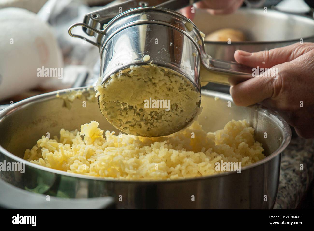 Schiacciare le patate per preparare la purea Foto Stock