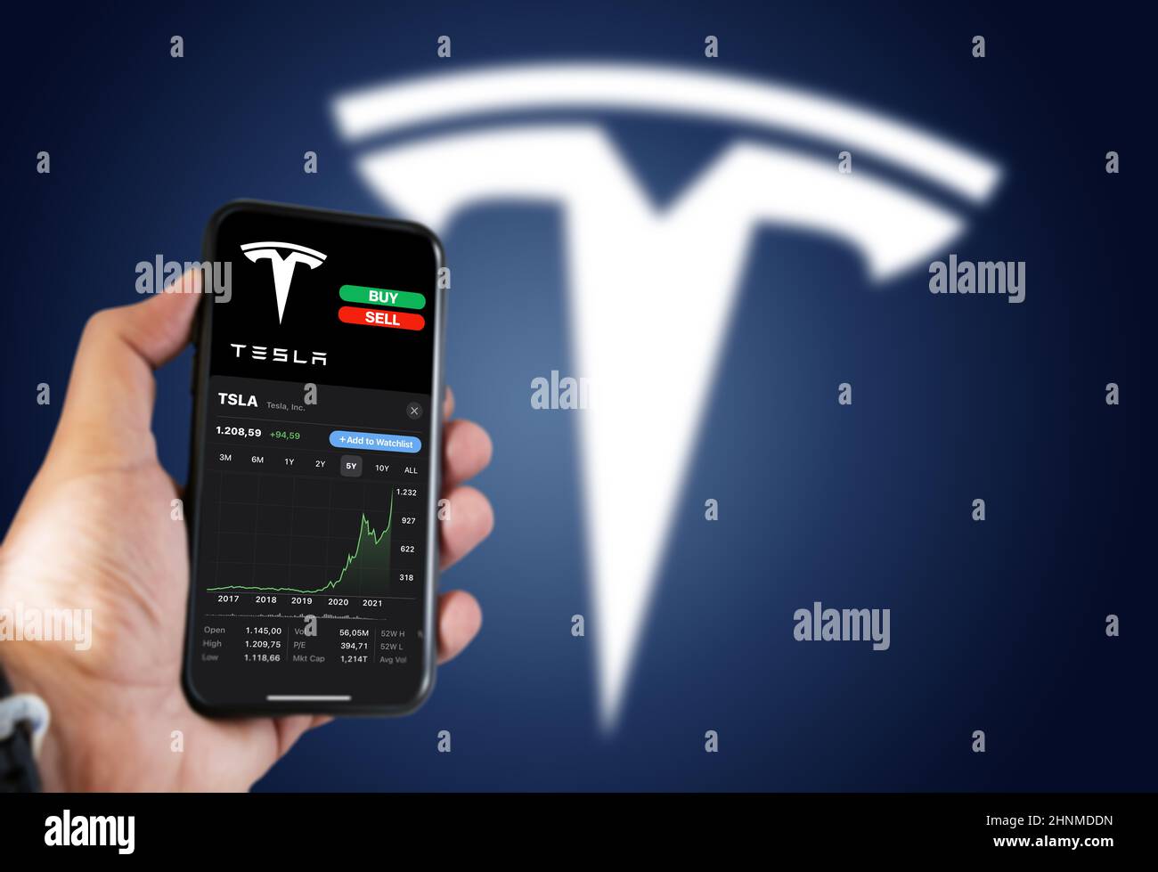 Tenere a mano un telefono con la tabella delle scorte Tesla Motors e i pulsanti di acquisto e vendita sullo schermo Foto Stock