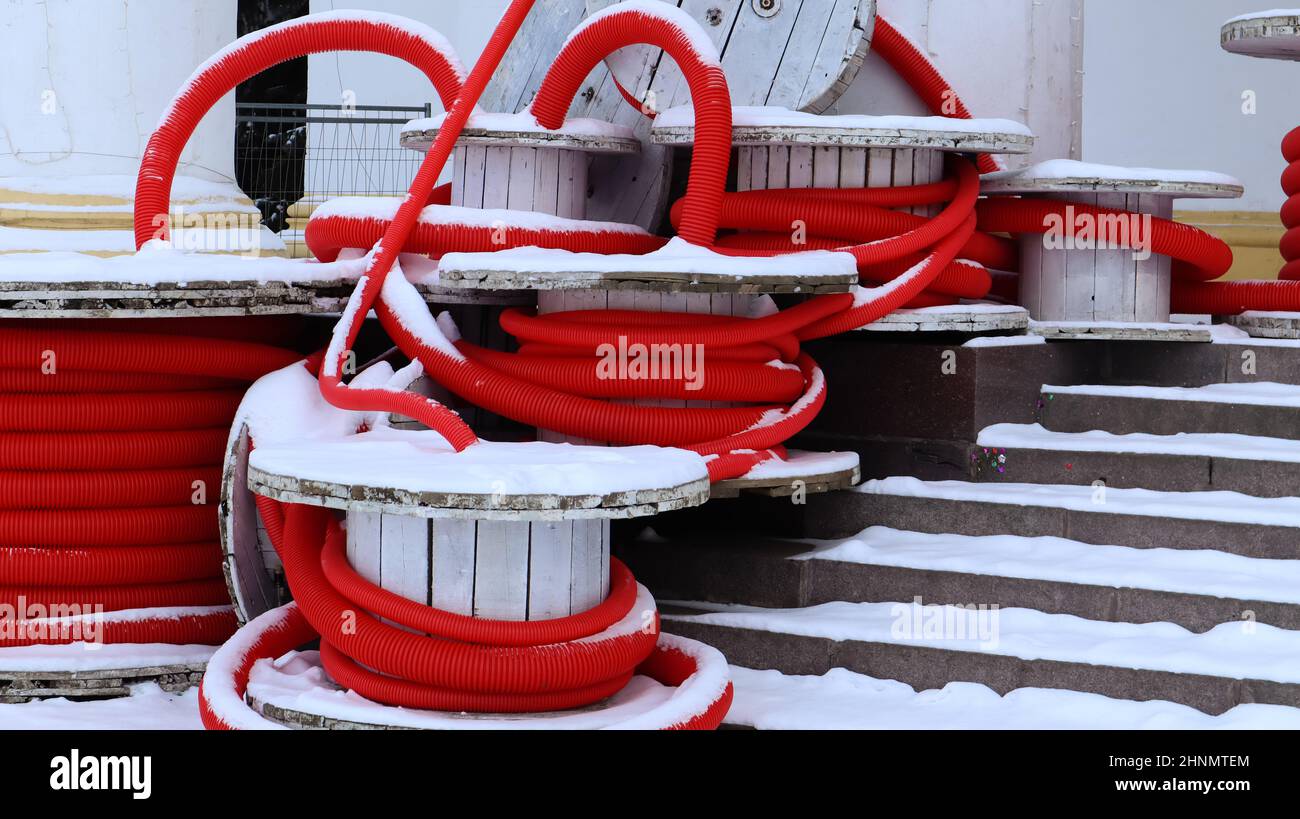 Grandi bobine di tubo corrugato rosso flessibile utilizzato per proteggere i cavi negli impianti elettrici. Un sacco di tubi flessibili in plastica di polietilene colorati utilizzati nella costruzione per impianti idraulici. Foto Stock