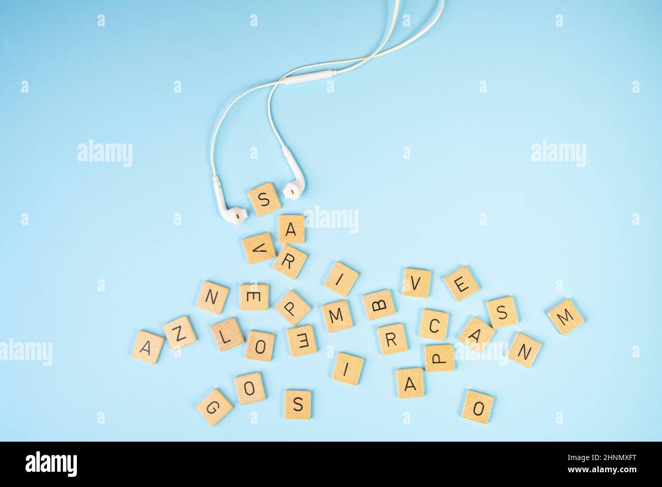 Le lettere su blocchi di legno e un paio di cuffie su una superficie blu Foto Stock