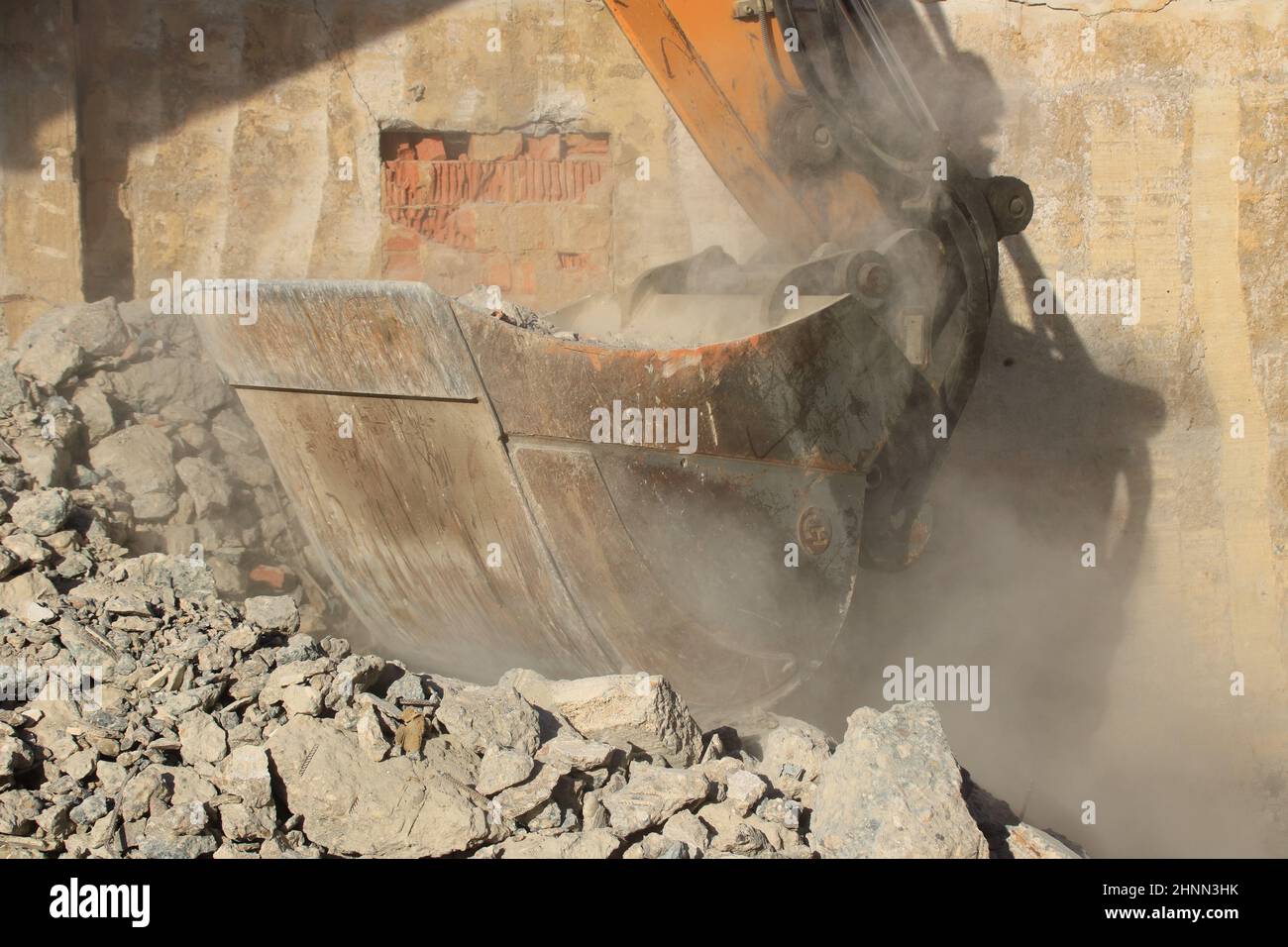 Caricamento di macerie da costruzione con un escavatore in un ambiente polveroso Foto Stock