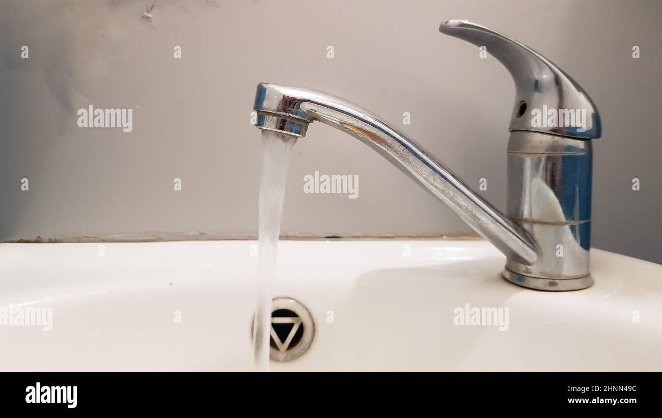 Rubinetto vecchio e sporco e lavabo in ceramica bianca, concetto di pulizia, riparazione o sostituzione di un bagno, wc. Foto Stock
